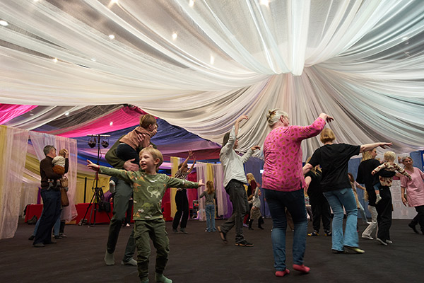 Barn och vuxna som dansar under ett luftigt tygtak